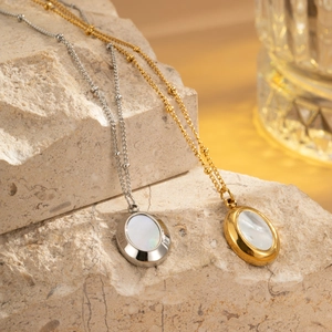 Detail of gold and silver oval shell pendant necklaces on a natural textured stone base