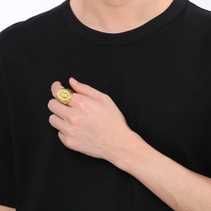 Detailed view of a gold signet ring with coin relief engraving worn on a finger