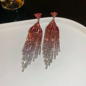 Detailed close-up of geometric tassel earrings with red and silver gradient rhinestones