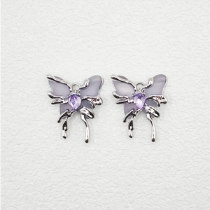 Detail of silver butterfly earrings with translucent purple wings and drop-shaped gemstone