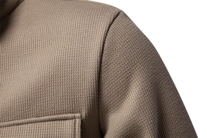 Detailed close-up of brown waffle knit fabric and pocket stitching on men jacket
