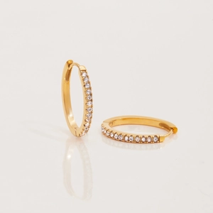 Detail of 18K gold stainless steel hoop earrings with sparkling white diamonds on white base