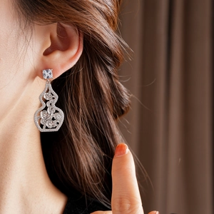 Macro shot of a hollow gourd earrings with flower details worn by a model on her earlobe