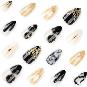 Short almond press-on nails featuring black floral designs and gold foil accents