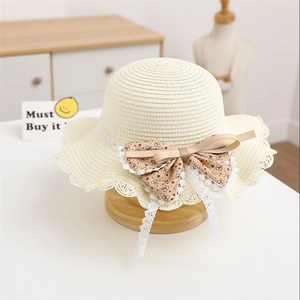 Detail of cream straw hat with floral brown bow and lace trim on wooden stand