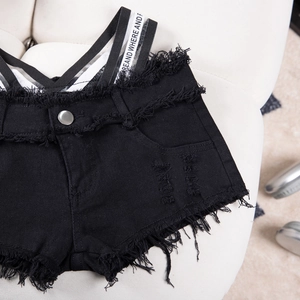 Dettaglio degli shorts in denim nero con cinturini decorativi e bordi sfilacciati a mano