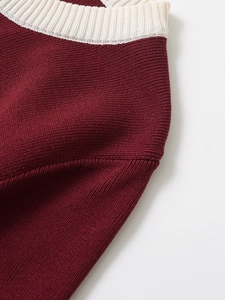 Close-up of burgundy knitwear with cream trim showing ribbed collar and fine stitching