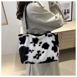Close-up of fluffy cow print plush underarm bag with black leather shoulder strap