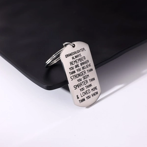 Close-up of engraved stainless steel dog tag keychain for granddaughter with inspirational text