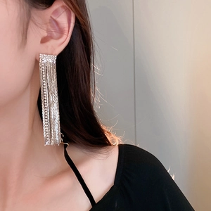 Detailed close-up of a long silver tassel earring with sparkling rhinestones on a model