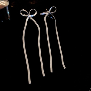 Detail of silver bow earrings with sparkling rhinestones and long tassel drop chains