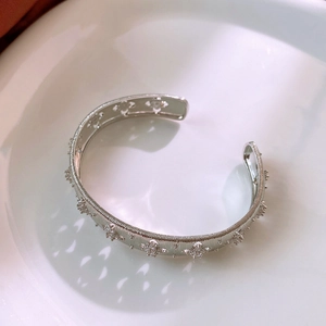 Macro detail of silver floral wide bangle with vertical brushing and zircon clusters
