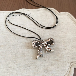 Detailed macro view of the leopard print bow pendant on a black cord necklace