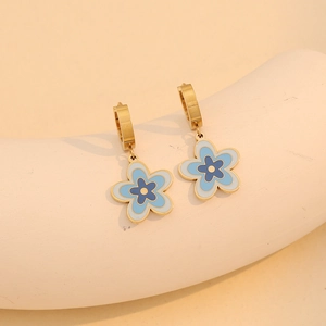 Elegant gold flower hoop earrings with blue enamel petals on a soft minimalist display