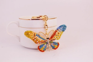 Close-up of a colorful butterfly keychain with vibrant rhinestones on a pink background
