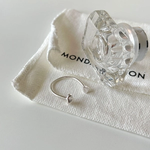 Detail view of S925 sterling silver open ring with 3D heart charms on white fabric