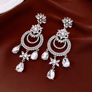 Détail de boucles d'oreilles vintage en argent et cristaux sur soie de luxe