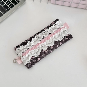 Detailed macro view of quilted floral fabric with white lace trim and flower zipper pull
