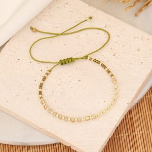 Detail of bohemian woven beaded bracelet on a stone tray with natural textures