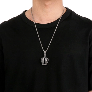 Close-up of a silver punk hip-hop crown pendant with diamonds on a black shirt