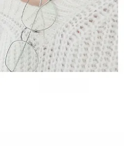 Macro shot of silver metal round frame glasses paired with a white knitted sweater