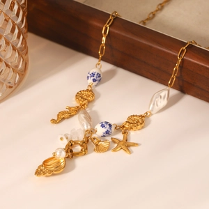 Gold ocean necklace detail with starfish, shell, seahorse charms and baroque pearl