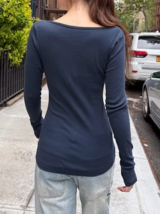 Street view of navy long sleeve slim fit top for women paired with light blue jeans