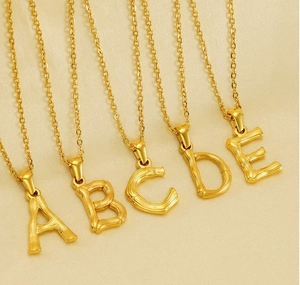 Detailed view of gold initial necklaces with unique bamboo textured chains and pendants