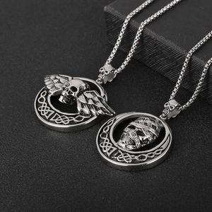 Detail of silver angel wing skull and mummy pendant with Celtic knot on black texture