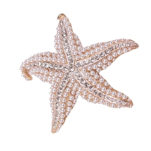 Golden starfish brooch with pavé rhinestones and pearls on a white background
