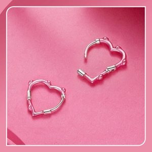 Detail of pink heart-shaped earrings with bamboo texture silver clasp on pink background