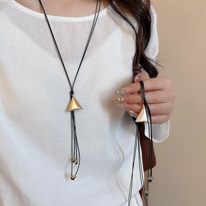 Close-up of double-layered geometric triangle pendant necklace on a white linen shirt