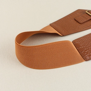 Detail of wide brown waist belt featuring crocodile texture and elastic braided band