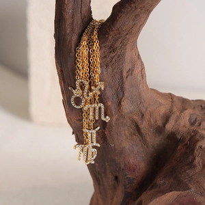 Gold-plated zodiac necklaces with crystals hanging on rustic wood in a chic setting