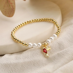 Detail of hummingbird charm with red gemstone and white zircon on pearl bead bracelet