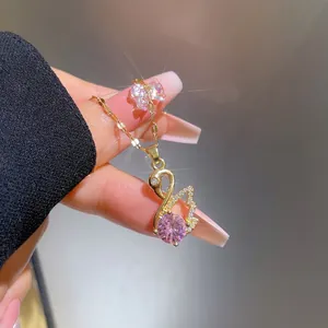 Close-up of a gold-plated swan pendant with pink crystal and micro-pave zirconia details
