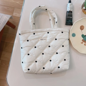 White quilted tote bag with black polka dots and simple wish tag on white desk