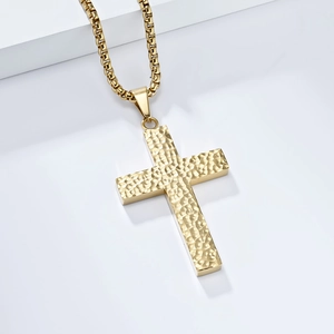 Détail du collier croix en acier doré présentant une texture martelée artisanale unique
