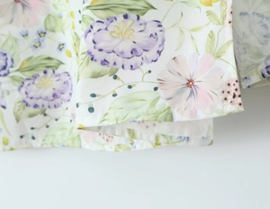 Gros plan sur le motif floral violet et rose et les détails de couture de l'ourlet de robe