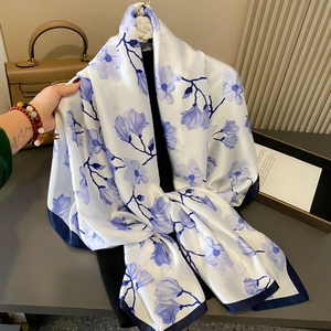 Elegant white silk scarf with blue floral prints and navy borders on mannequin