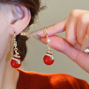 Close-up of vintage gold snake earrings with red beads and shimmering crystal accents