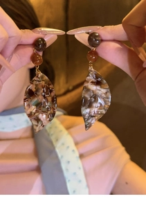 Detail showing vintage leaf pendant earrings with marble resin texture and gold metal link
