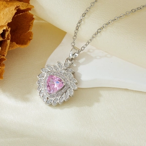 Macro shot of silver necklace with pink heart gemstone and sparkling diamond halo