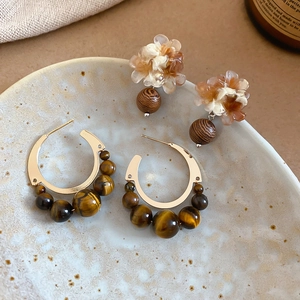Détail de boucles d'oreilles vintage fleurs en résine avec perles œil de tigre et bois