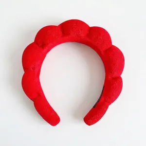Close-up of a thick red braided sponge headband for face washing and makeup application