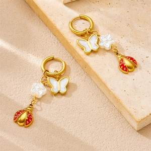Golden hoop earrings with cute butterfly, ladybug, and flower charms on stone surface