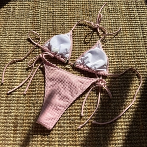 Detail of pink bikini with bubble texture fabric and seashell charms on jute mat