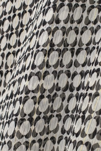 Macro view of geometric chiffon fabric with black and white circles and gold metallic threads