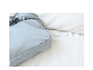 Close-up of light blue nylon fabric detail showing soft texture on white bedding