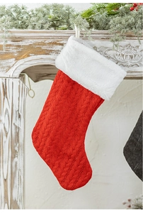 Detail of red cable-knit Christmas stocking with white plush trim on a festive fireplace